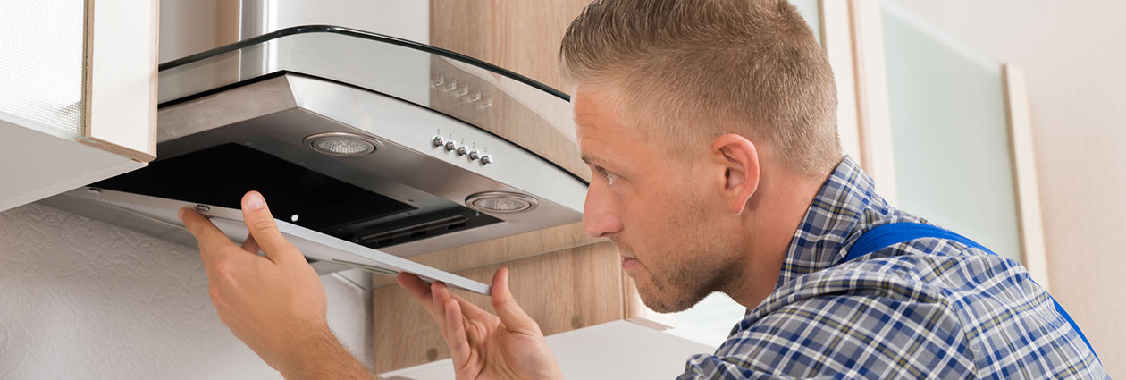 Man replacing filter above stovetop - Maintain Cooking Station - Keller Engineering