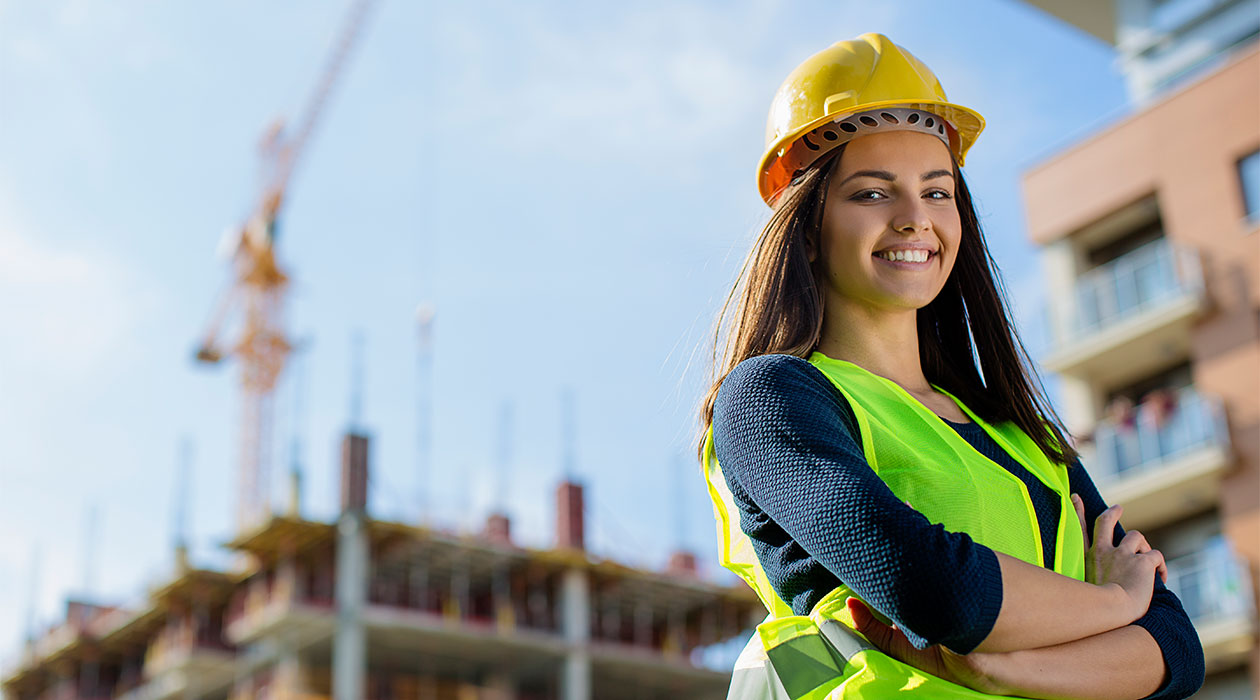 Female engineer stands in front of a building under construction