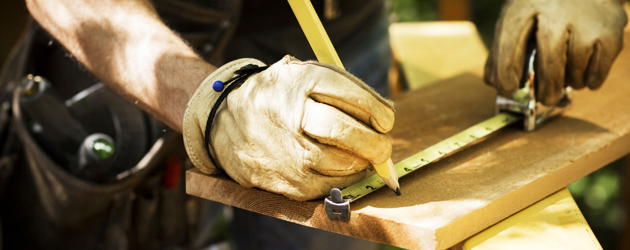 Close up of a builder using a tape measure on a plank of wood