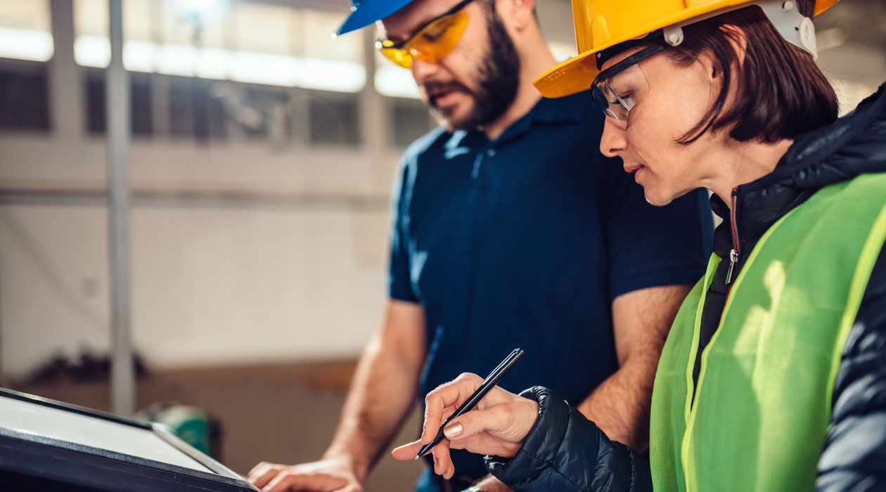 Two engineers in hardhats preparing a report