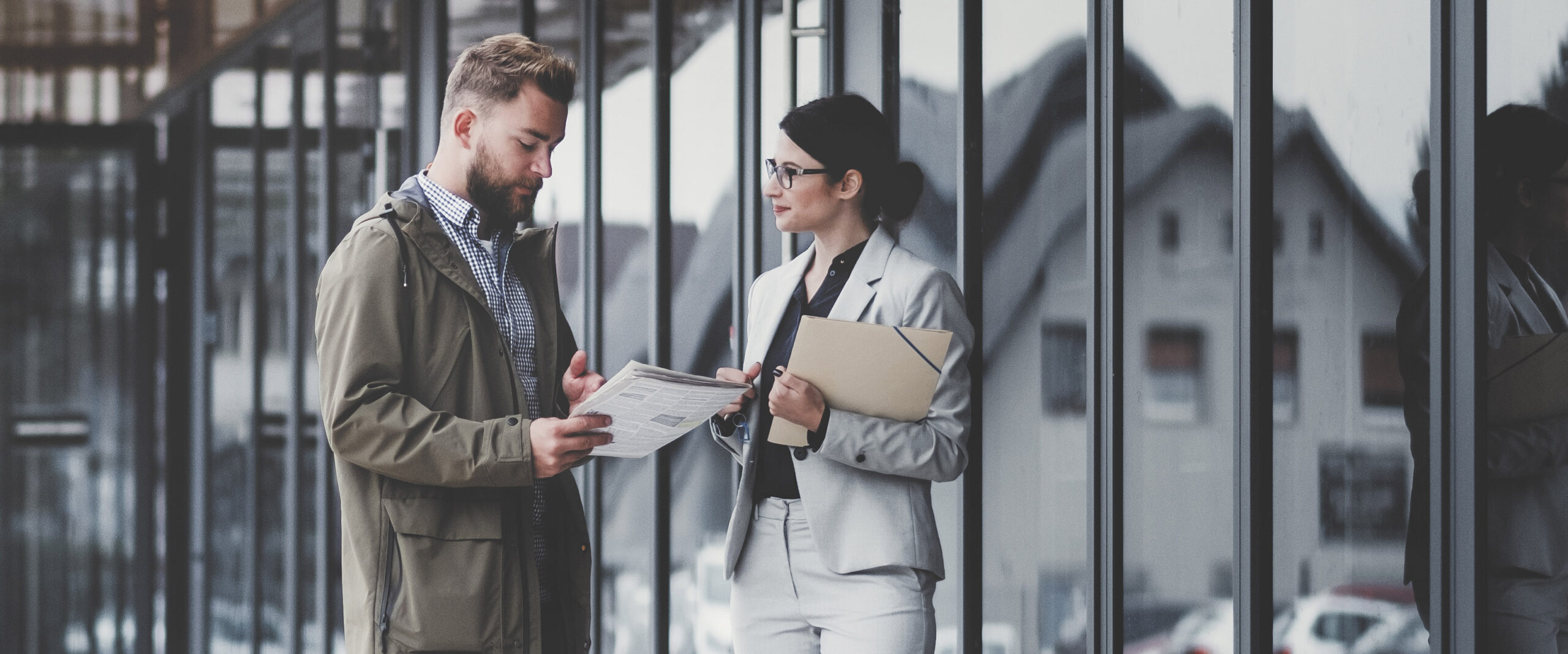 Real estate agent and customer looking for apartment. Image taken at average residential area with multiple ownership block of flats type of buildings.