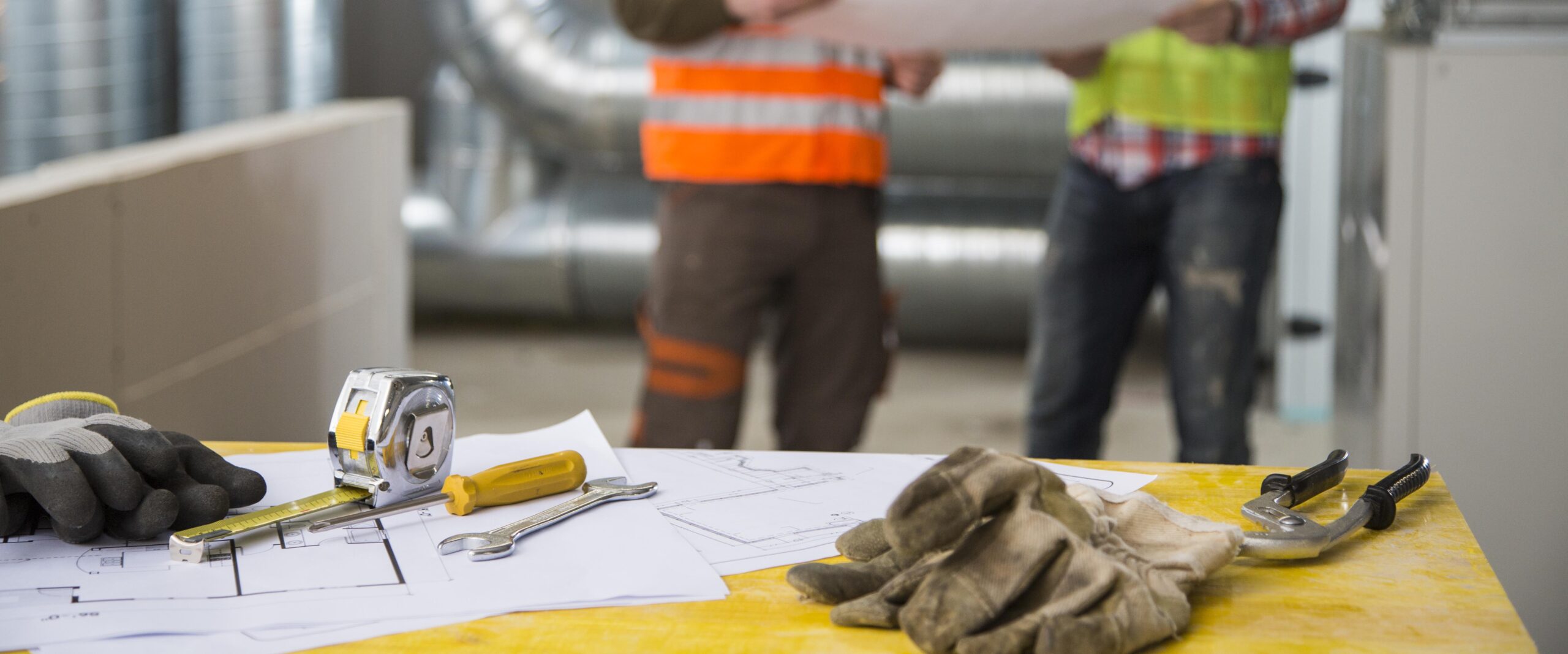 Two Construction workers, Engineers or Architects discuss Building Project on site. Inside of construction site. HVAC Engineering.