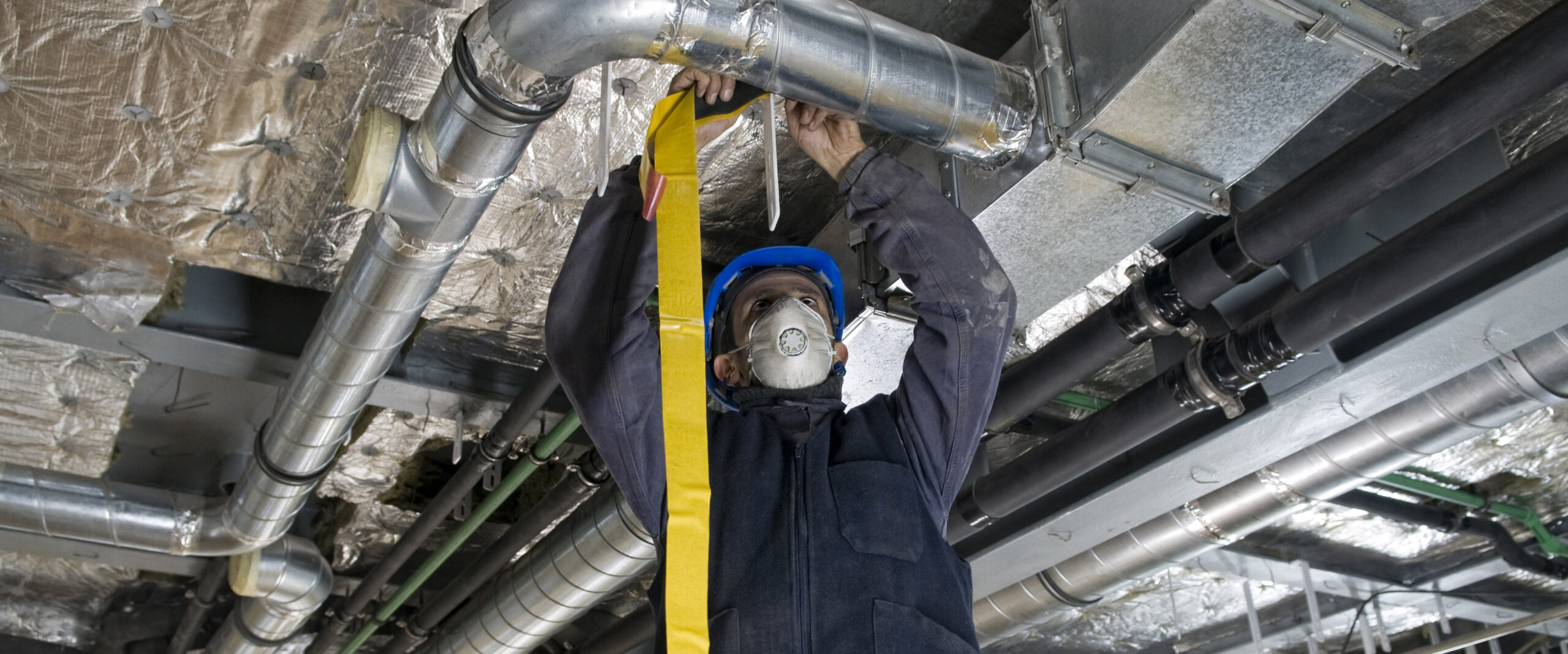 Worker Wrapping an HVAC Air Duct with Foil Tape