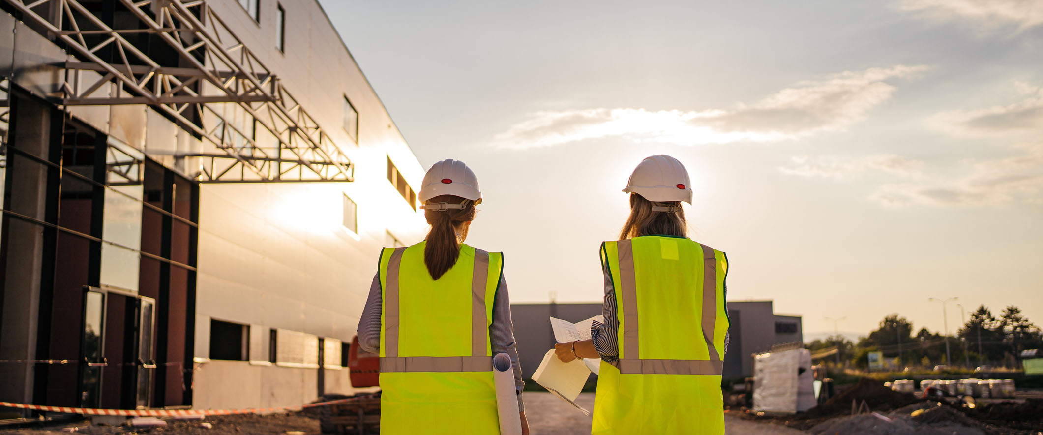 Female construction engineers with helmet walking through the construction site and making plans for their project.